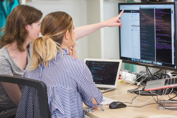 two developers in front of a screen with code on it